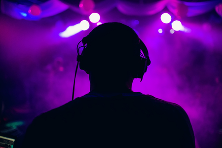 DJ with headphones performs at a music concertの写真素材