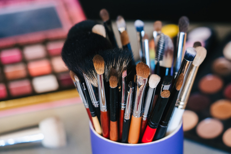 set of professional makeup brushes on the background of pallets with eye shadowsの写真素材