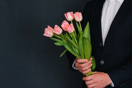 bouquet of pink tulips in the hands of a man