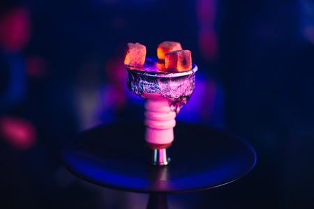 hot red coals of tobacco on the bowl of Shisha on the foil close up