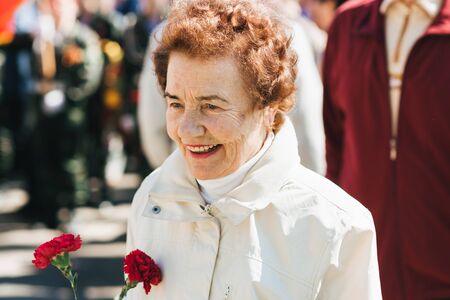 VICHUGA, RUSSIA - MAY 9, 2018: Portrait of a happy smiling old woman at parade in honor of victory...