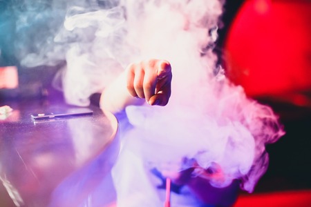 man smokes a hookah and breathes a large cloud of tobacco smokeの写真素材