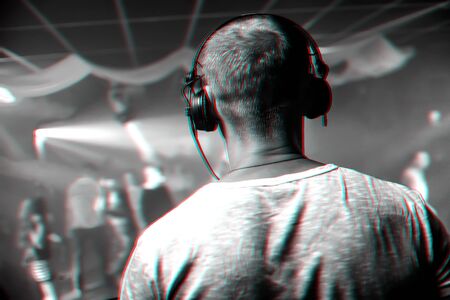 head of a DJ with headphones playing at the event in a nightclub. Black and white photo with glitch effect and small grainの写真素材
