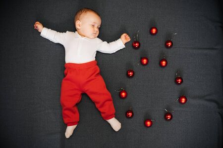 sleeping baby boy lying with Christmas ballsの写真素材