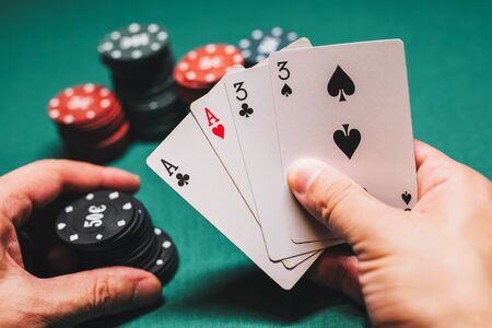 Playing poker in the casino. Cards with two pairs in the hand of the player making a bet with chipsの写真素材