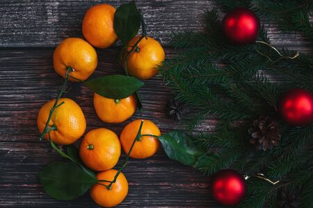 tangerines, fir branches, red balls and cones on a Christmas backgroundの写真素材