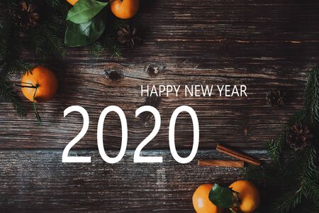 greeting card with tangerines with fir branches on a wooden background and the inscription Happy New Year 2020の写真素材