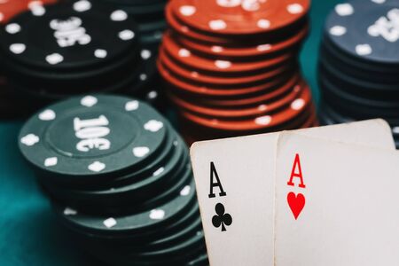 One pair of aces and playing chips in a game of poker on the background of a green table closeup