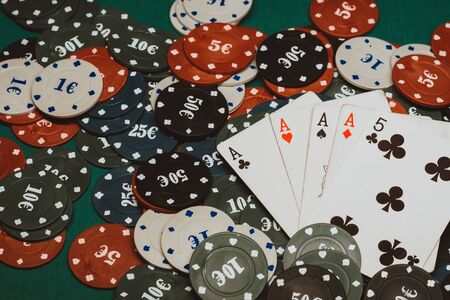 four of a kind of aces in poker on the background of the green table in the casino with gaming chips...