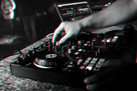 hands of a DJ in a booth playing on the mixer
