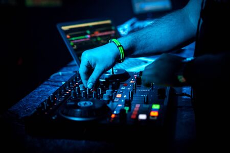 hand DJ mixing music on a professional controller Board in a nightclub