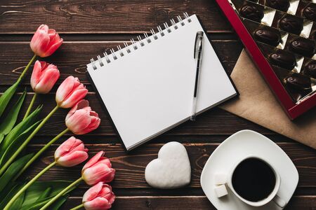 bouquet of pink Tulip flowers and a Cup of coffee with a box of sweet chocolates on the wooden tableの写真素材