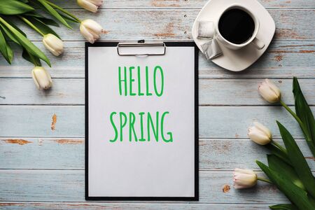 Greeting card with lettering Hello Spring. Bouquet of white Tulip flowers with a Cup of coffeeの写真素材