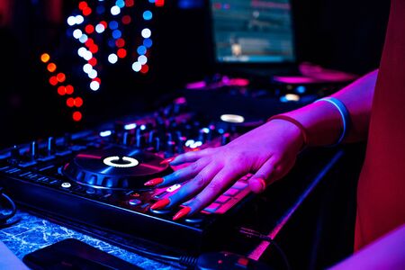 hand of a DJ girl on the background of a music controller mixerの写真素材