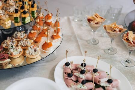 canapes with bacon, olives, cheese, cucumber and red fish on the festive table in the restaurant for a delicious appetizerの写真素材