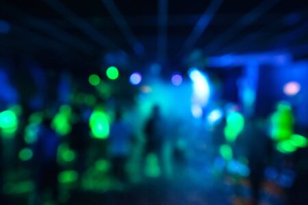 blurred silhouettes of a group of people dancing in a nightclub on the dance floor under colorful...