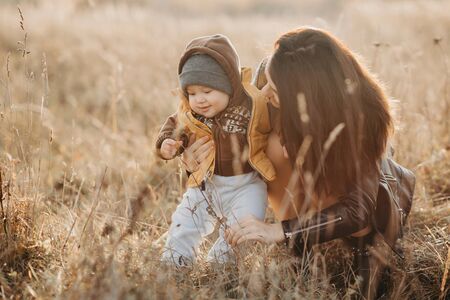 young mom playing with her little baby boy son in autumnの写真素材