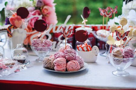 candy bar with marshmallows and cupcakes decorated with flowers and butterfliesの写真素材