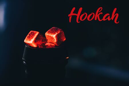 Hot red coals for hookah in a bowl on a dark background close up
