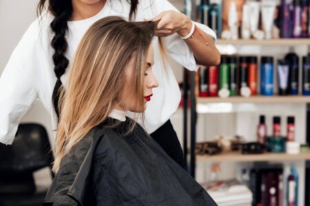 hairstylist makes a hairstyle for a woman with light brown long hair