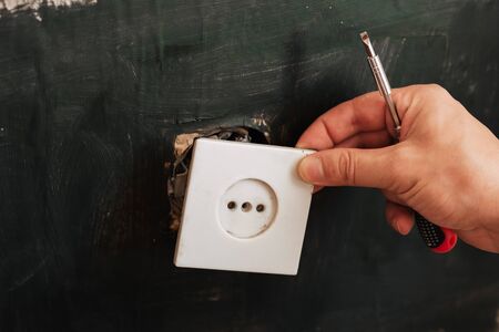 male electrician removes an old electrical outlet