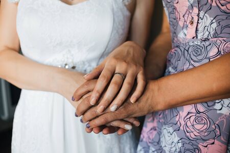 mother holds her daughter bride by the hands on the wedding day close-up