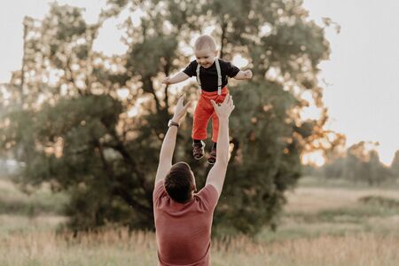 dad tosses up a happy little son in a field in the summerの写真素材