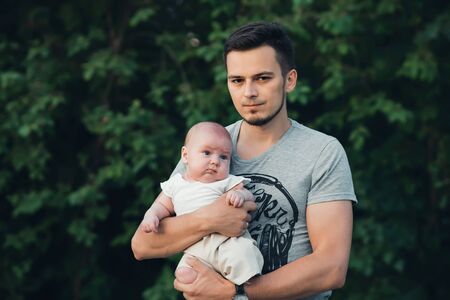 young happy dad with a newborn son boy child in hands