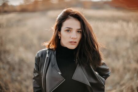 portrait of a fashionable young Caucasian brunette girl in a leather jacketの写真素材