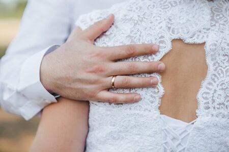 hand groom with gold wedding ring gently hugs the brideの写真素材