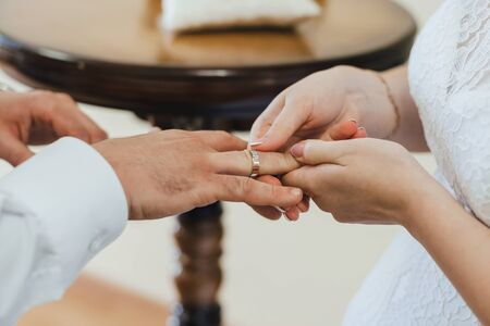 bride puts a gold wedding ring on the finger of the groom. Traditional wedding ceremony