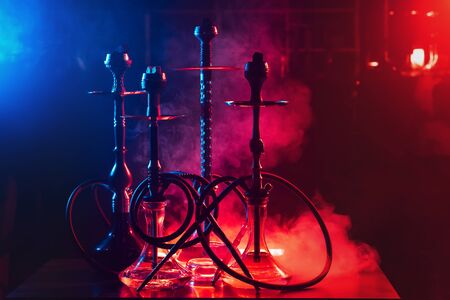 hookahs on the table with smoke and red and blue light in the lounge cafe. Concept of traditional Eastern Arabic relaxing with a shishaの写真素材