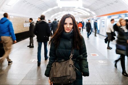 Young Caucasian girl at a metro station and a crowd of moving people with blurの写真素材