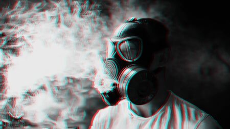 man in a gas mask smokes a hookah and breathes a cloud of tobacco smokeの写真素材