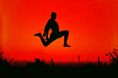 silhouette of a sporty man jumping high in nature on a summer morning against the skyの写真素材