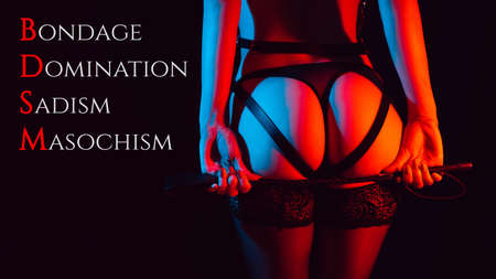 Sexy ass girl in a leather belt with a whip in her handsの写真素材