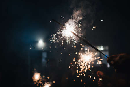 Sparkler glittering sparks in a persons hand at the celebrationの写真素材