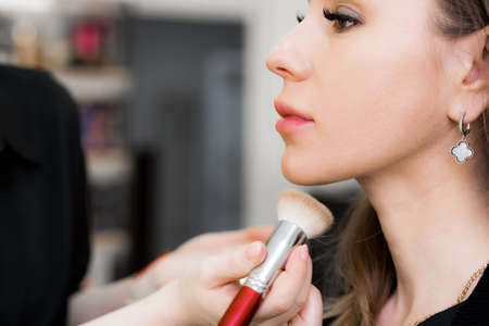 makeup artists hand with a shadow brush making make-up on a womans faceの写真素材