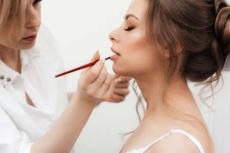 beautiful girl makeup artist makes make-up and paints her lipsの写真素材