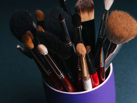 set of professional makeup brushes on dark background