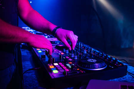 hands of a DJ playing music on a mixer at a concertの写真素材
