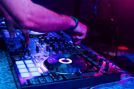 hands of a DJ mixing music on a professional controller in a booth