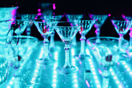 empty glasses from cocktail with illumination of ultra violet color