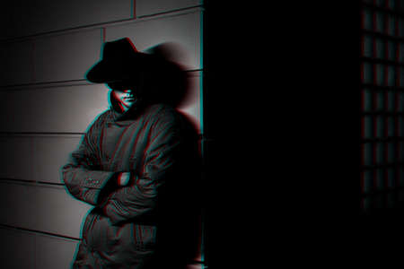 dark silhouette of a man in a raincoat with a hat at night