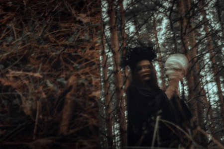 blurry mystical reflection of a black witch with a skull in her hands performing a satanic ritualの写真素材