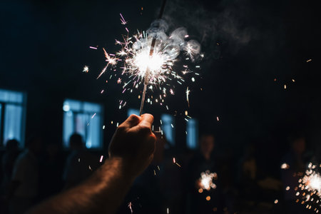 Sparkler glittering sparks in a persons hand at the celebrationの写真素材