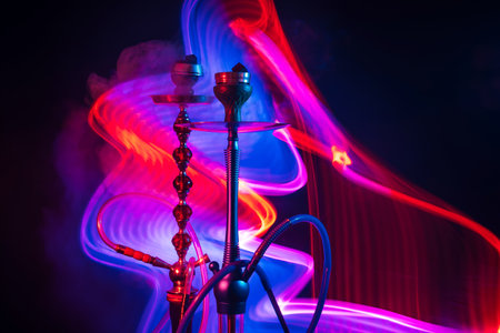 two hookah bowls with shisha charcoals with smoky smoke with blue red neon lightsの写真素材
