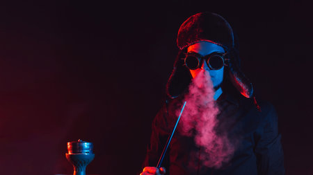 bearded man smokes a shisha in a hookah bar and blows a cloud of smoke