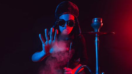 bearded man smokes a shisha in a hookah bar and blows a cloud of smoke