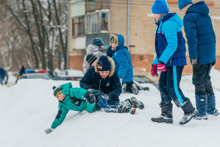 VICHUGA, RUSSIA - FEBRUARY 17, 2018: Competition between children on a snow slide at the traditional Russian Slavic celebration of the Maslenitsaのeditorial素材